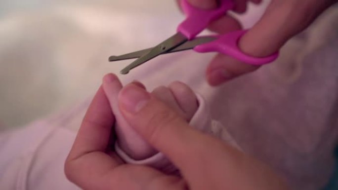 妈妈用手握着婴儿的指甲，她拿着小剪刀，让孩子们剪指甲而不会伤害婴儿
