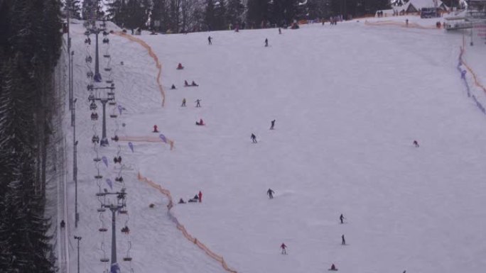 晴天，滑雪者和滑雪者在滑雪胜地的雪坡上骑行