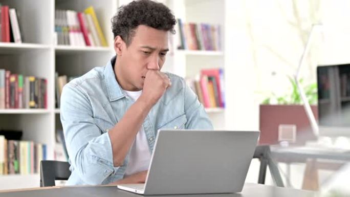 咳嗽的年轻非裔美国人在笔记本电脑上工作