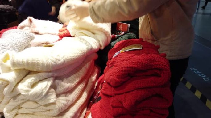 买家在商场里挑选一件毛衣。