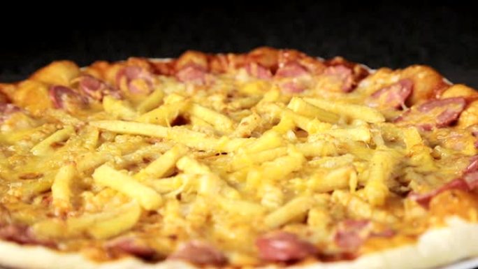 在顶部的黑色背景视图中，带有奶酪西红柿，香肠和鸡蛋的比萨饼的特写镜头围绕自己旋转