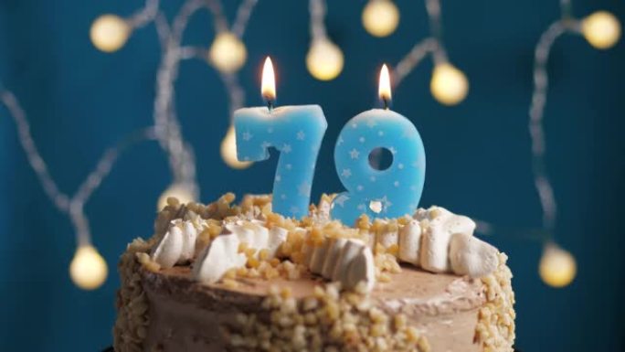蓝色背景上有79号蜡烛的生日蛋糕。蜡烛吹灭了。慢动作和特写视图
