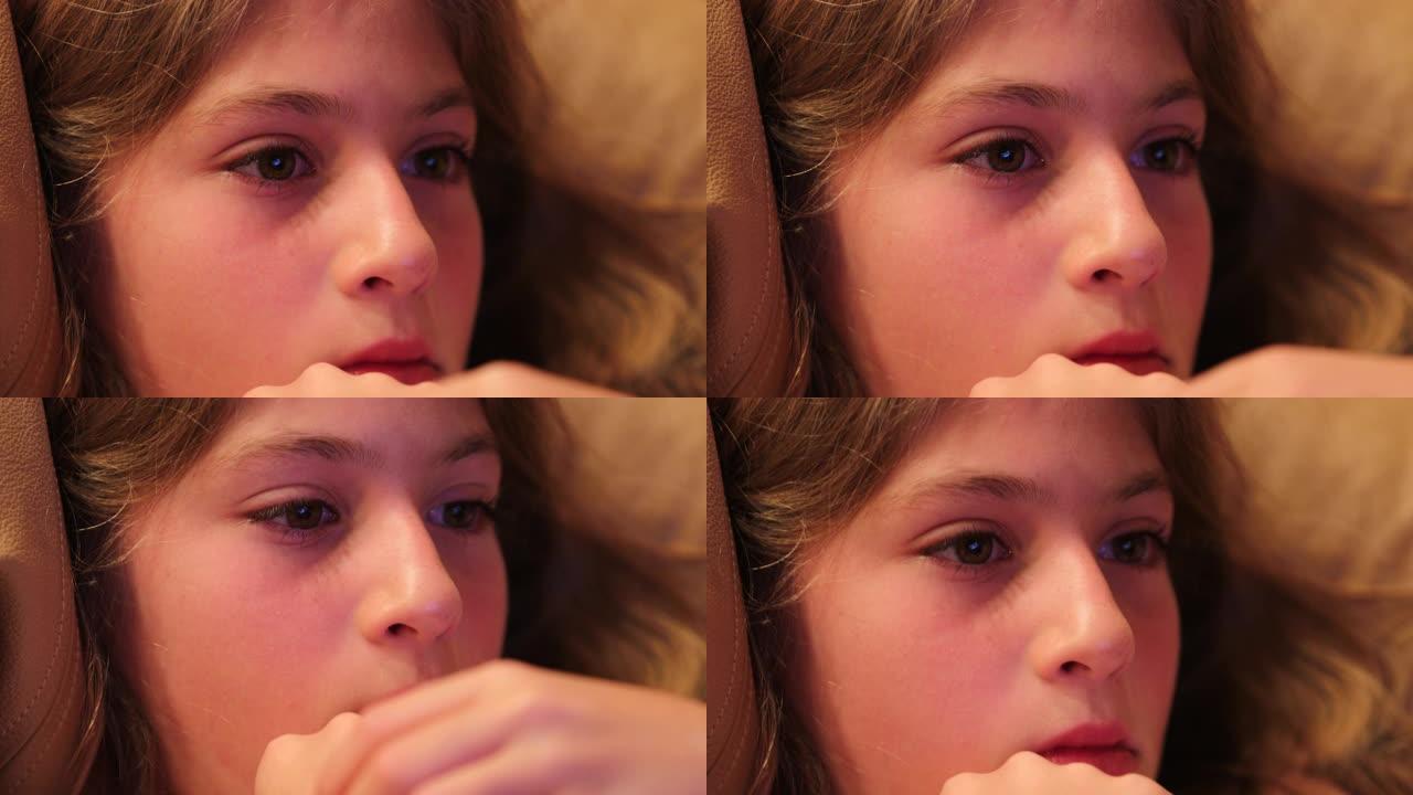 儿童女孩在家看电影时被屏幕内容吸收的孩子脸特写