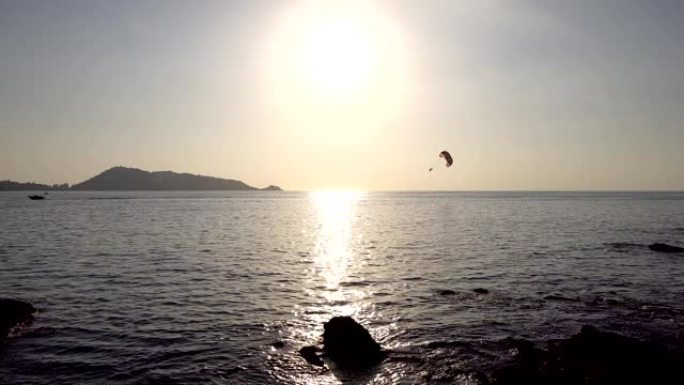 美丽的阳光日落在金色黄昏日落时平静的海洋水面在地平线上美丽的风景夏天黄昏黄昏和旅行的人玩滑翔伞在海上