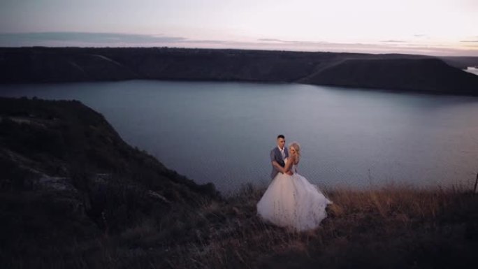 新婚夫妇在河边的一座山上。日落。新郎和新娘