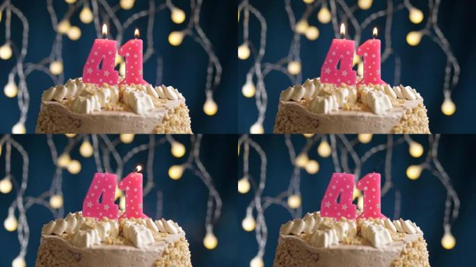 蓝色背景上有41号粉色蜡烛的生日蛋糕。蜡烛吹灭了。慢动作和特写视图