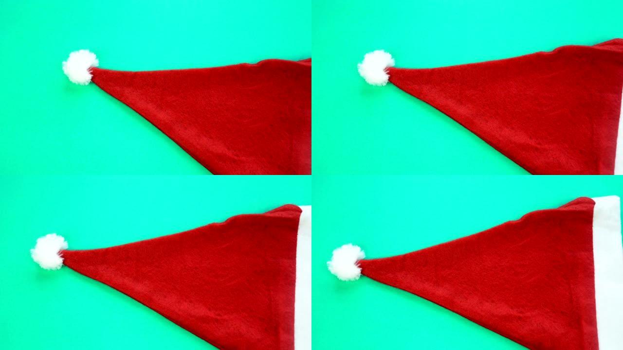 绿色背景上的红色圣诞老人帽子。圣诞背景