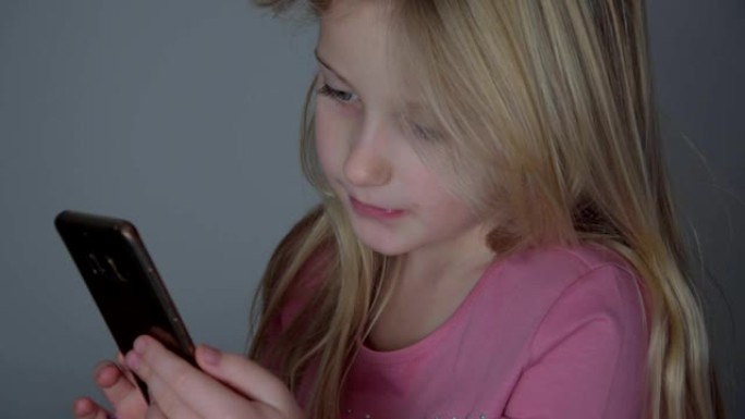 粉红色的小女孩在家里的轻便卧室里玩手机