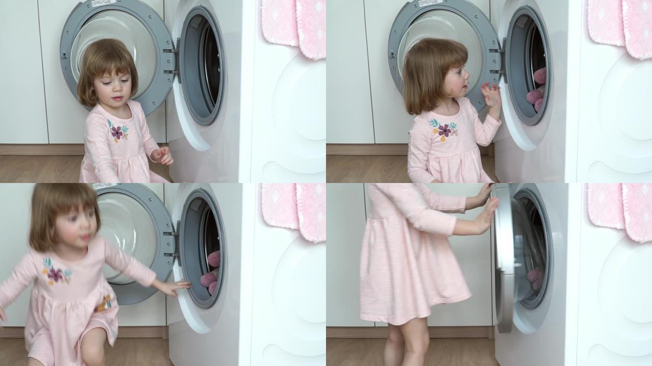 微笑的3岁小女孩的肖像坐在地板上，放在洗衣机的毛绒玩具中进行洗涤。儿童洗涤玩具