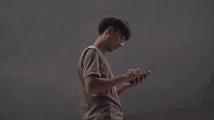 亚洲男子戴眼镜使用手机和站立