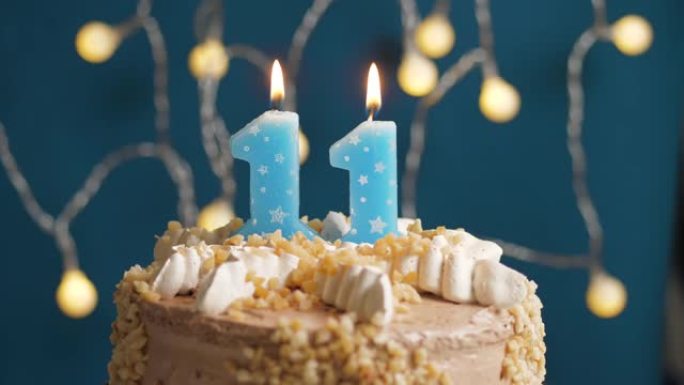 蓝色背景上有11号蜡烛的生日蛋糕。蜡烛吹灭了。慢动作和特写视图
