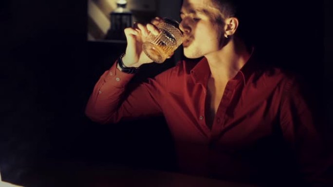 穿着红色衬衫的男人正在酒吧喝威士忌