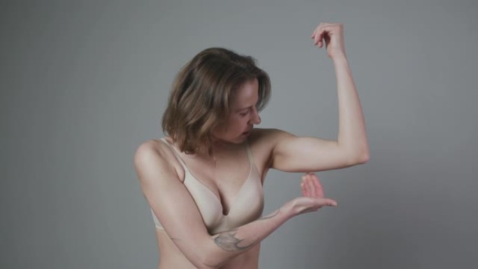 减肥概念。女人捏上臂脂肪。高加索女性手部检查松弛皮肤的特写。身体控制。该节食了