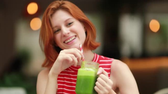 快乐红发女孩喝排毒绿汁微笑着笑