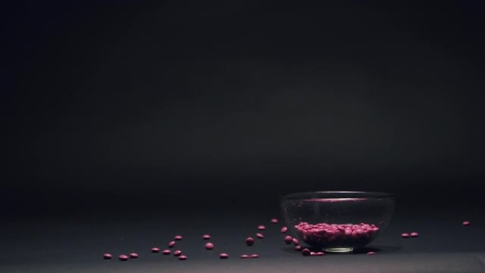 黑色黑板纹理背景上的复制空间慢动作落在玻璃碗里的粉色糖果