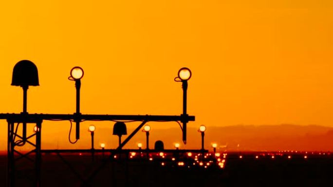 机场跑道边缘灯指示飞机飞行员的着陆路径。灯架着四个侧面的圆形灯和中间的单个大频闪。橙色日落背景下的天