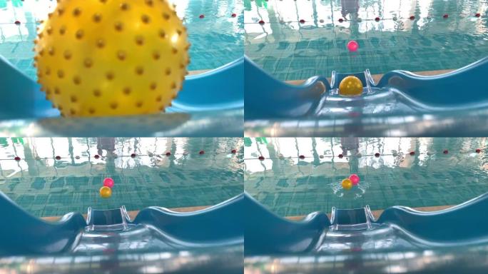 黄色球在水滑梯上滚落到游泳池