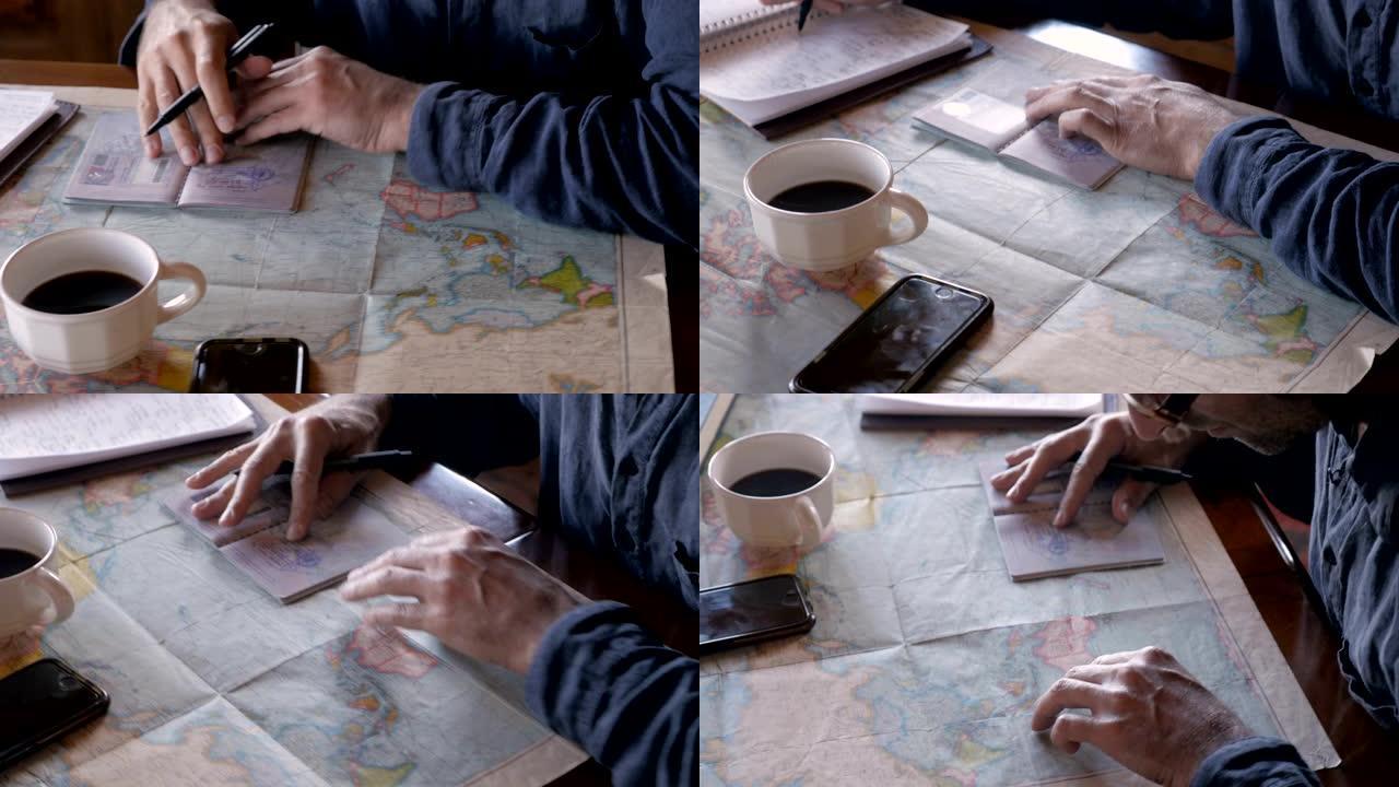 男子在笔记本上写字时看着他的护照邮票和世界地图