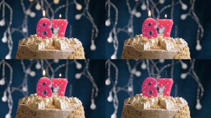 蓝色背景上有67号粉色蜡烛的生日蛋糕。蜡烛吹灭了。慢动作和特写视图
