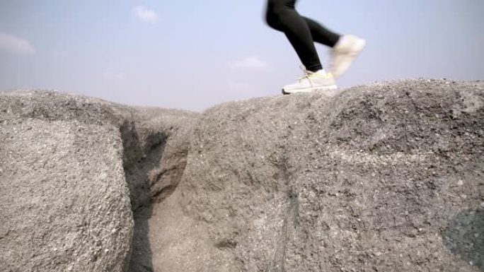 慢动作，在岩山瓦砾高空跳跃中近距离跑步，运动员健康女性运动跑步者专业户外困难和挑战健康人的生活方式