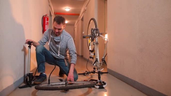 一名男子将空气泵入车库中的自行车车轮。