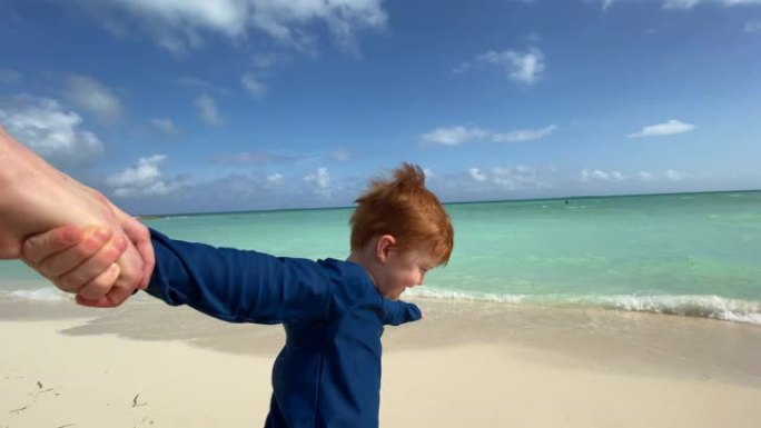 跟随我的概念 -- 在加勒比海的热带海滩上，红发男孩牵着母亲的手