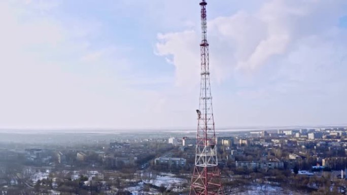 移动电话通信塔的空中轨道。发射塔在城市一侧阳光明媚的冬天，无人机镜头。电视塔耸立在小城市上空。