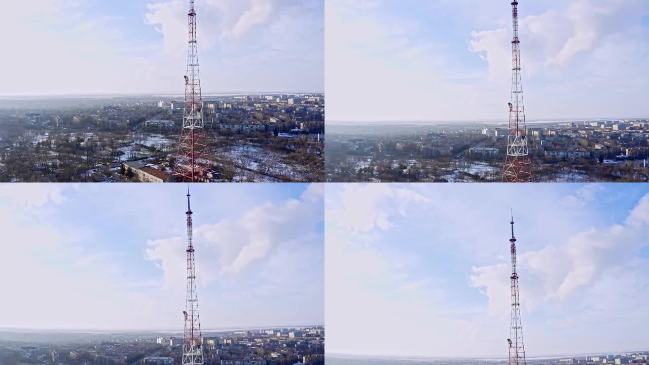 移动电话通信塔的空中轨道。发射塔在城市一侧阳光明媚的冬天，无人机镜头。电视塔耸立在小城市上空。