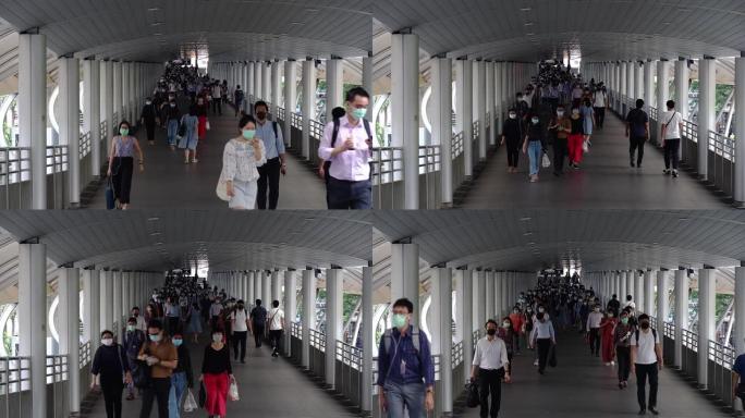 在泰国曼谷Chong-nonsi BTS站的公共交通系统工作人员之后，许多戴着卫生口罩的人在桥梁高峰