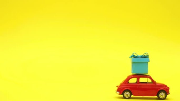红色复古汽车驾驶蓝色礼物在屋顶上黄色背景-停止运动