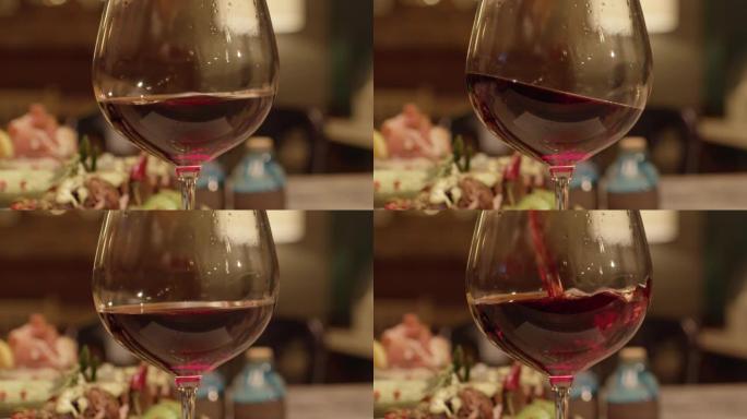 将红酒从瓶中倒入餐厅内的玻璃杯或高脚杯中的慢动作。红酒的特写在玻璃中形成美丽的波浪。在红色史诗电影相
