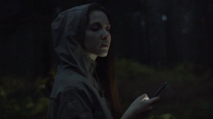 有吸引力的女性在户外使用智能手机。漂亮的年轻女孩游客在森林里迷路了，环顾四周查看地图上的路径。女学生