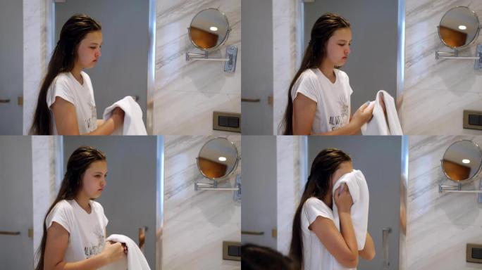 少女洗完后在镜子前用毛巾擦脸。