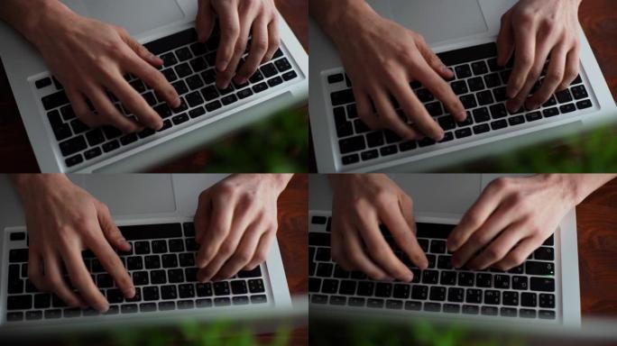 男士双手在桌子上笔记本电脑键盘上打字的特写镜头。