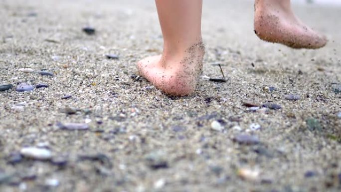 婴儿的脚在沙滩上做第一步，用波浪洗脚