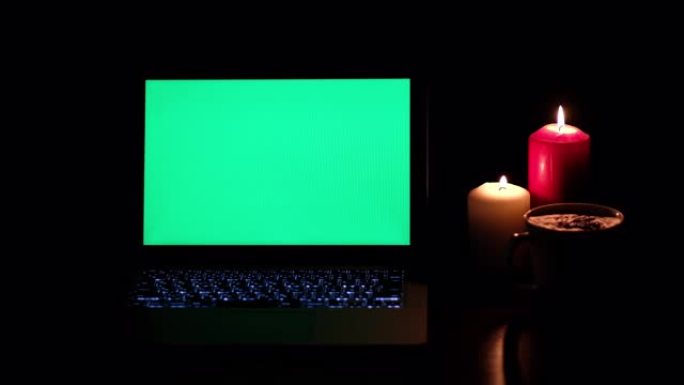 关闭桌子上的一台绿屏笔记本电脑，上面放着蜡烛灯和一杯咖啡。