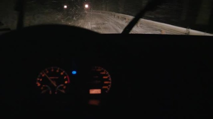汽车视点在夜间积雪覆盖的道路上行驶，第一场雪落下。