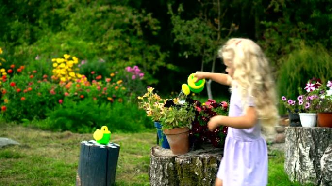 漂亮的金发小女孩用喷壶浇花