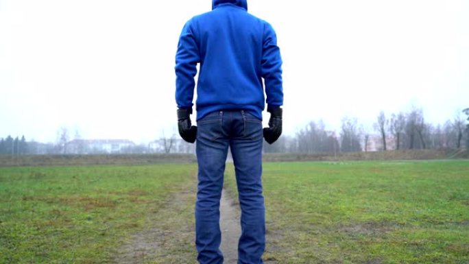 孤独概念，男人独自站在街上后视，戴着拳击手套，战斗生活，倾斜相机，仰视