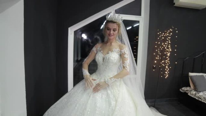 年轻漂亮的新娘头上戴着皇冠，别致蓬松的白色婚纱