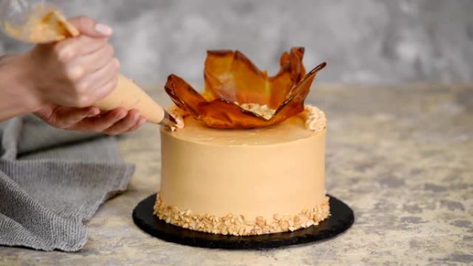 用焦糖奶油关闭女人的手装饰蛋糕。