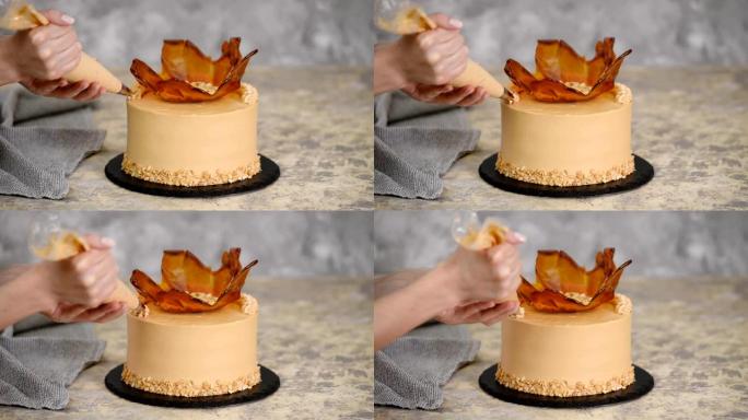 用焦糖奶油关闭女人的手装饰蛋糕。