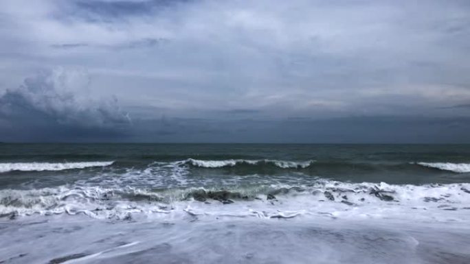 海浪袭击热带沙滩，天空多云