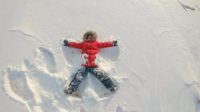 一个小男孩做了一个雪天使。冬季娱乐概念。慢动作镜头