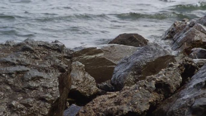 在阴天的夏季，海浪在湖附近的岩石上撞击