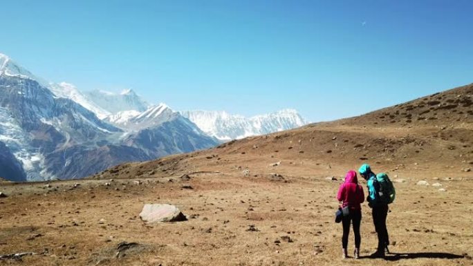 一对夫妇从尼泊尔喜马拉雅山安纳普尔纳巡回赛的一部分冰湖欣赏风景。安纳普尔纳链在后面，被雪覆盖。晴朗的