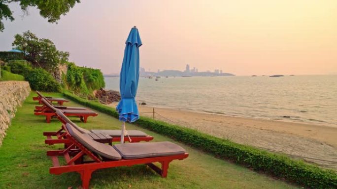 沙滩椅或泳池床和带日落和海洋背景的雨伞