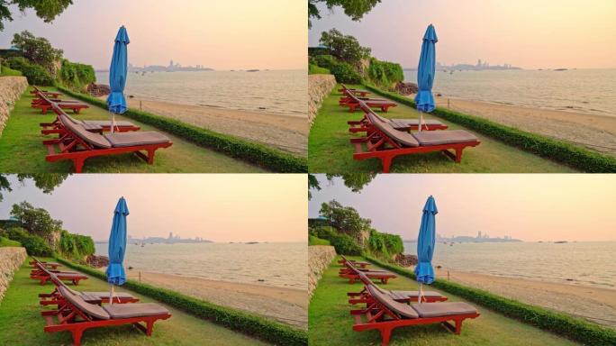 沙滩椅或泳池床和带日落和海洋背景的雨伞