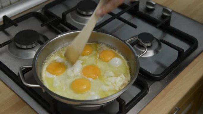 家庭主妇在钢锅中融化黄油以煎鸡蛋