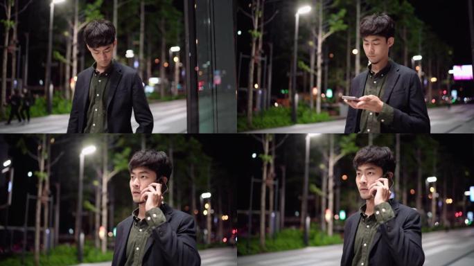 年轻的亚洲男子在夜间街头使用智能手机